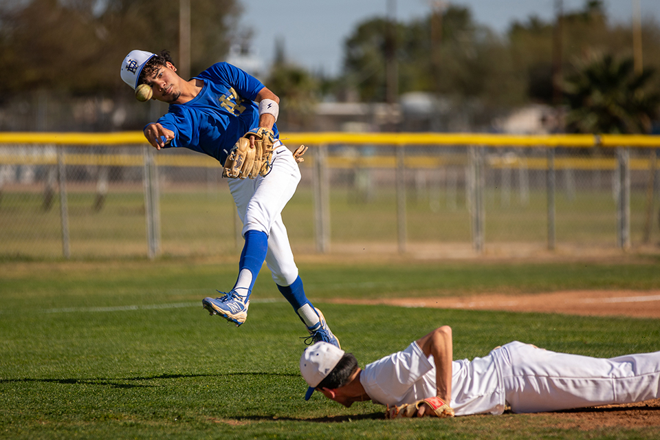 A Titan player slides into the base while an opponent throws the ball