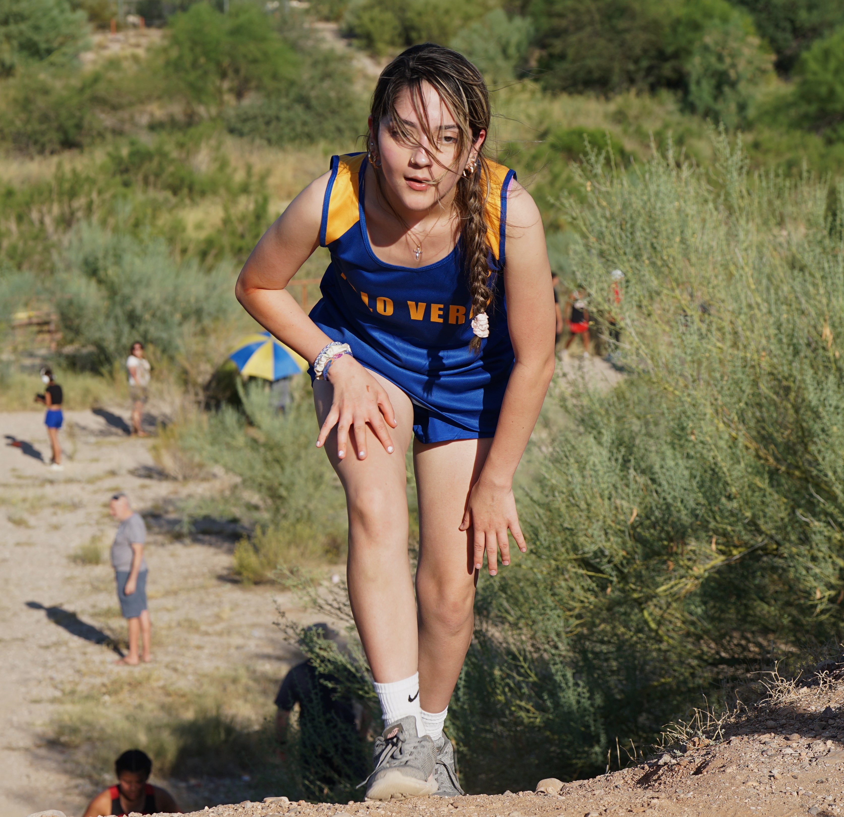 A Palo Verde cross country athlete puts her hand on her leg as she pushes up the final hill