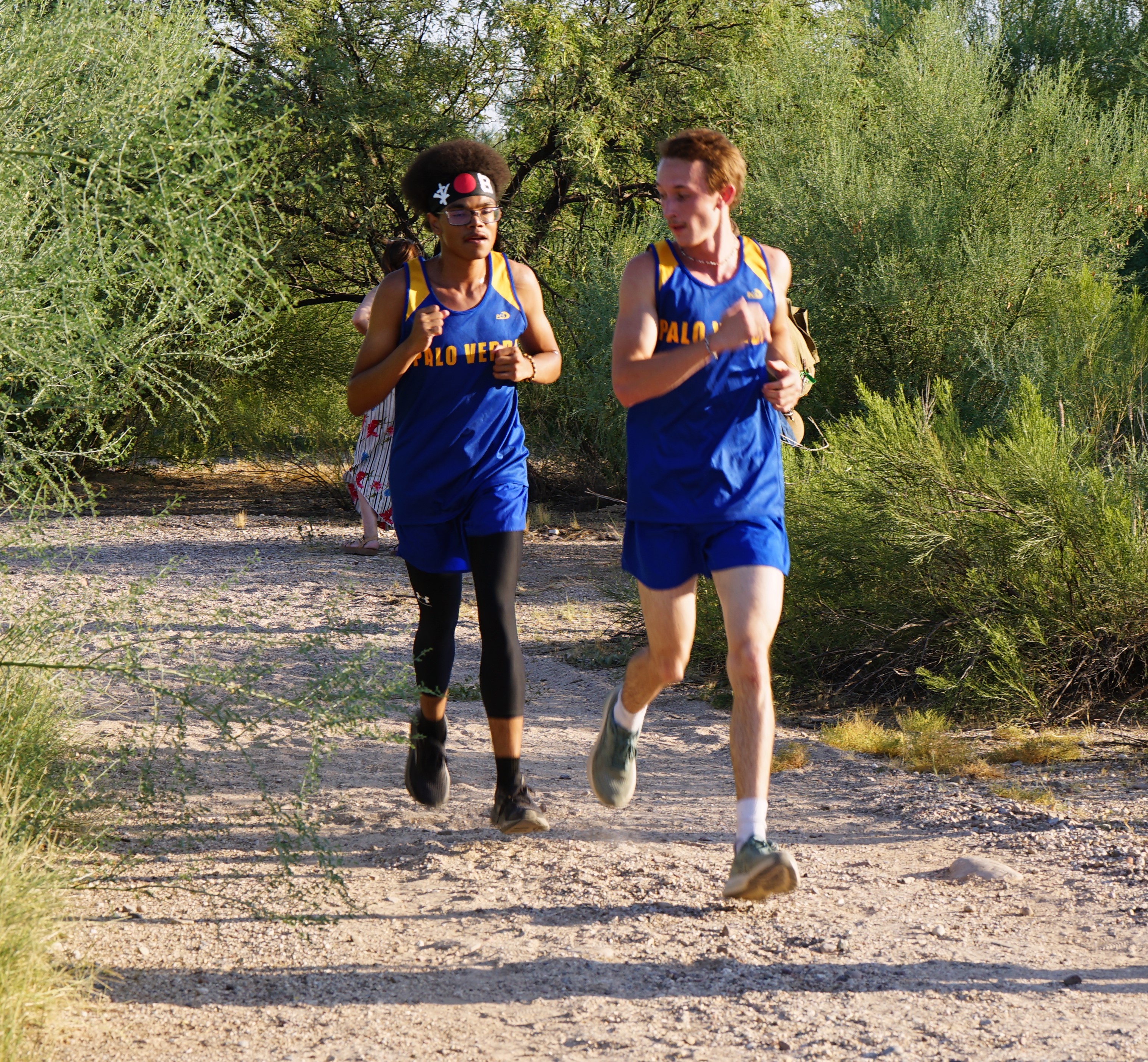 Two Palo Verde cross country athletes run through the mesquite trees on the course