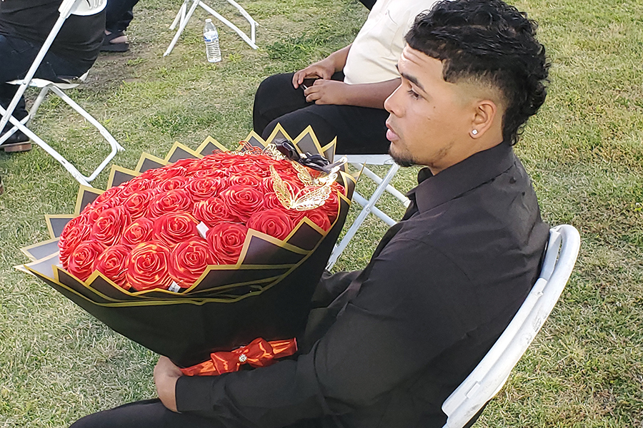 A teen boy holds a big bouquet of red roses
