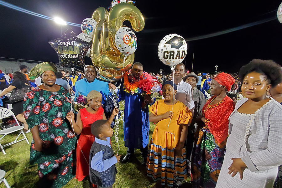 A graduate and his family hold giant balloons as they celebrate after the ceremony