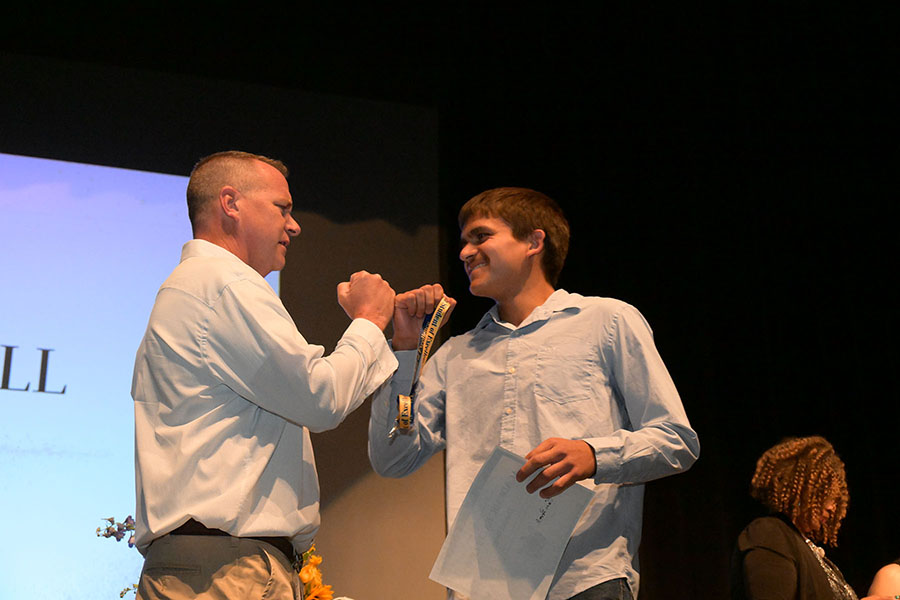 A teen boy fist bumps the principal