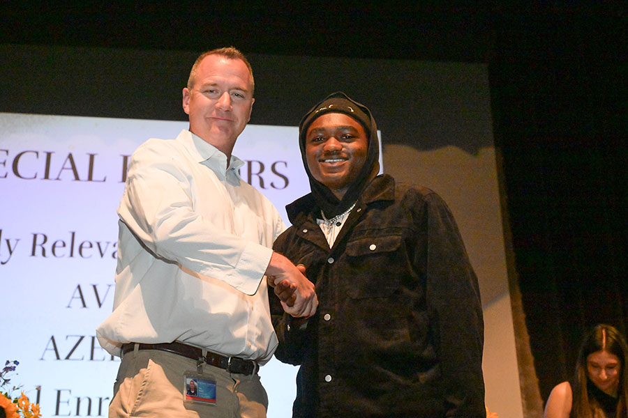 A teen boy shakes the principal's hand