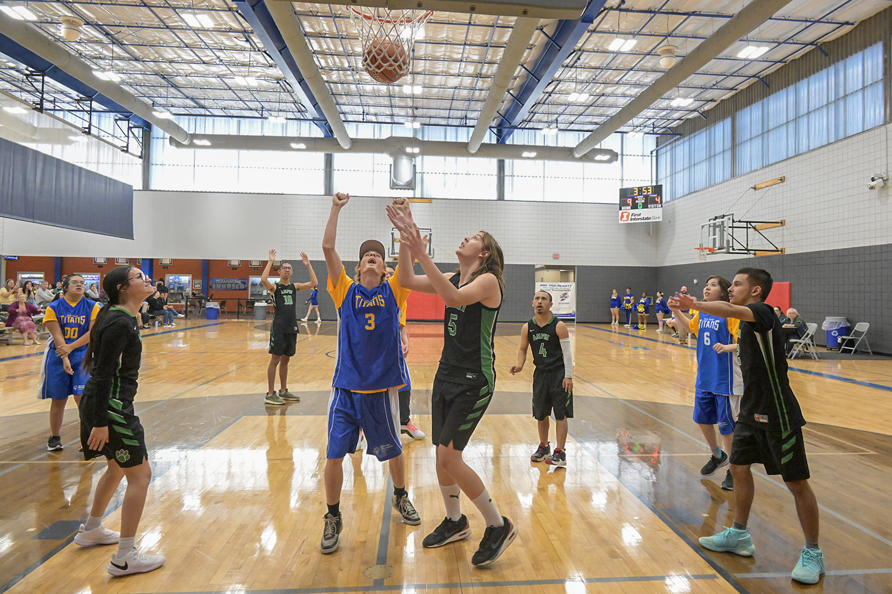 Two boys watch as a basketball goes into the hoop, as their teammates cheer them on