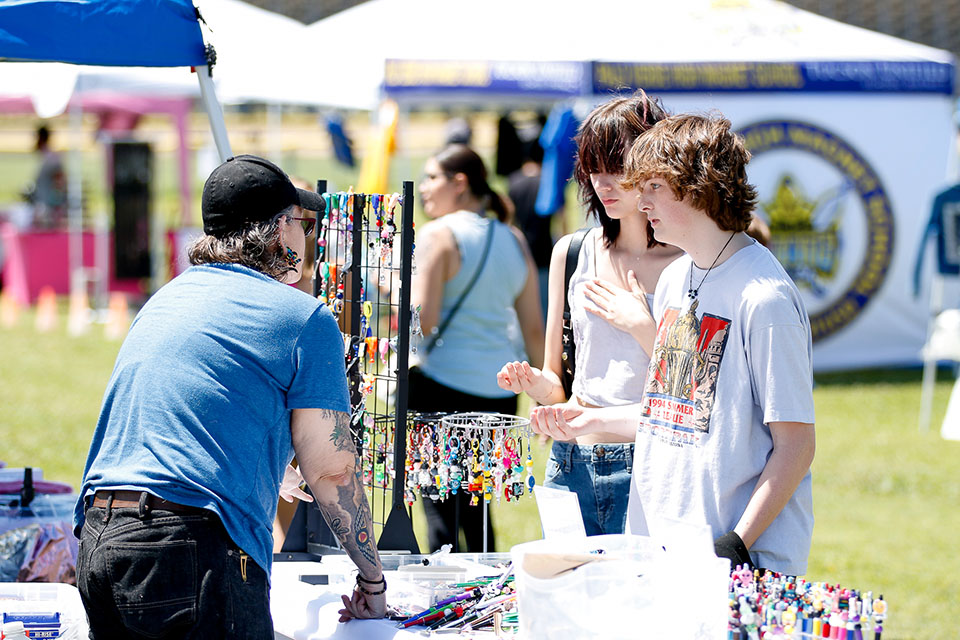 Students peruse a table with jewelry and other homemade crafts