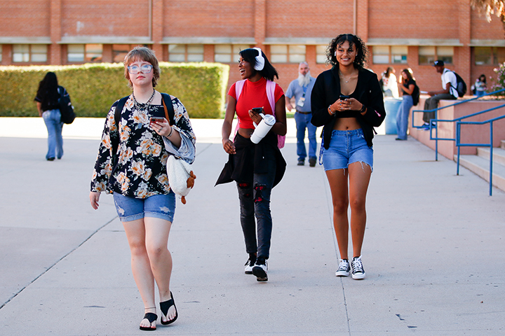 Three teen girls walk across campus 