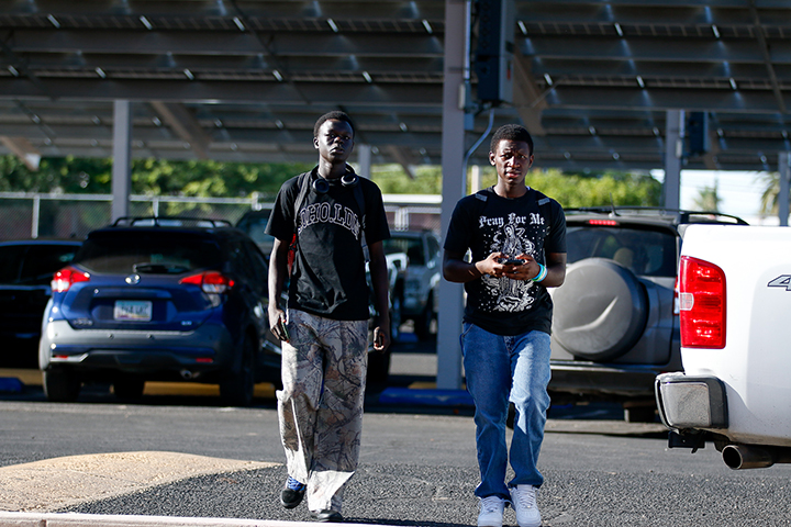 Two teen boys walk into school from the parking lot