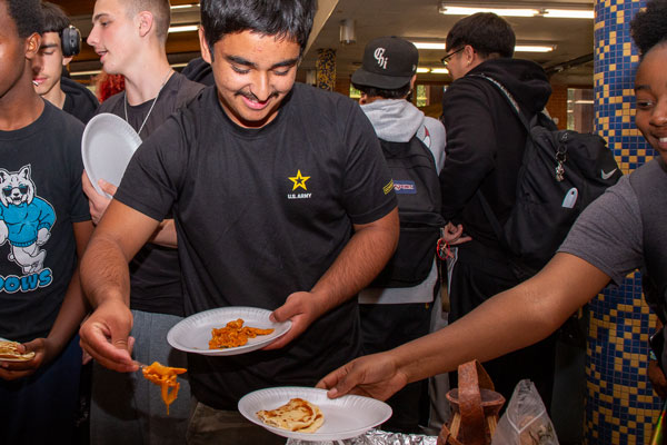 Students serve each other food.
