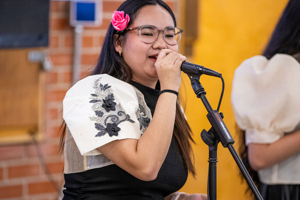 Student in Mexican garb speaks at a microphone.