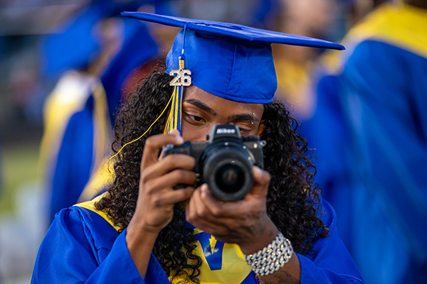 A graduate holds up his camera during the ceremony