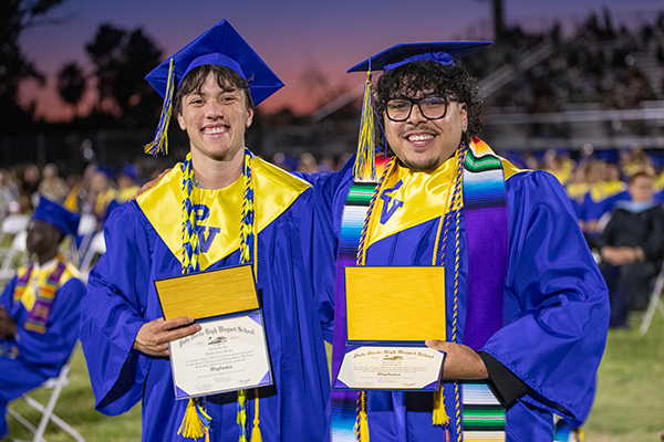 Two graduates pose together after the ceremony
