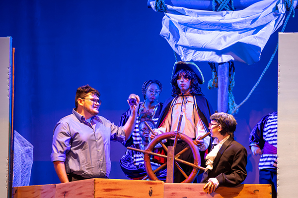 Students dressed up as fishermen act out a scene from The Little Mermaid on a ship