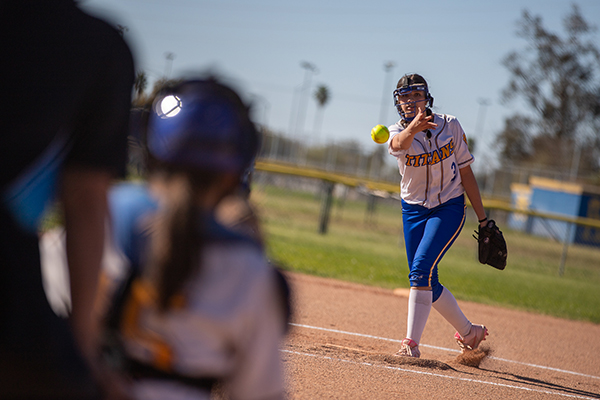 A girl tosses the softball to a teammate