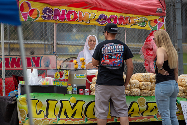 A man and woman browse the selections at a popcorn and snowcone vendor