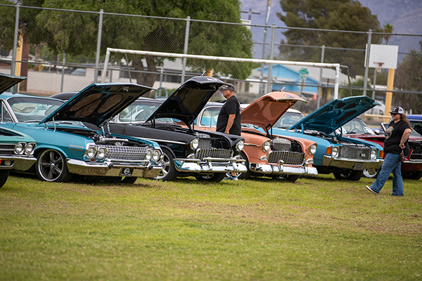 A man and woman walk past a line of classic cars
