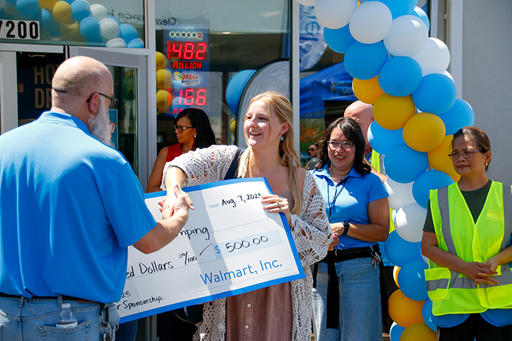 A woman in a crocheted top shakes a man's hand as she accepts a giant check for $500