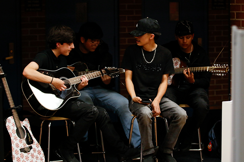 A group of teen boys tuning their guitars before a performance